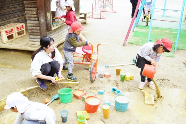 画像：園庭で遊ぶ幼稚園児と女性教諭