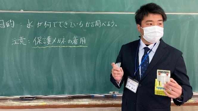 写真：黒板に書いた文字を見ながら生徒に説明する先生